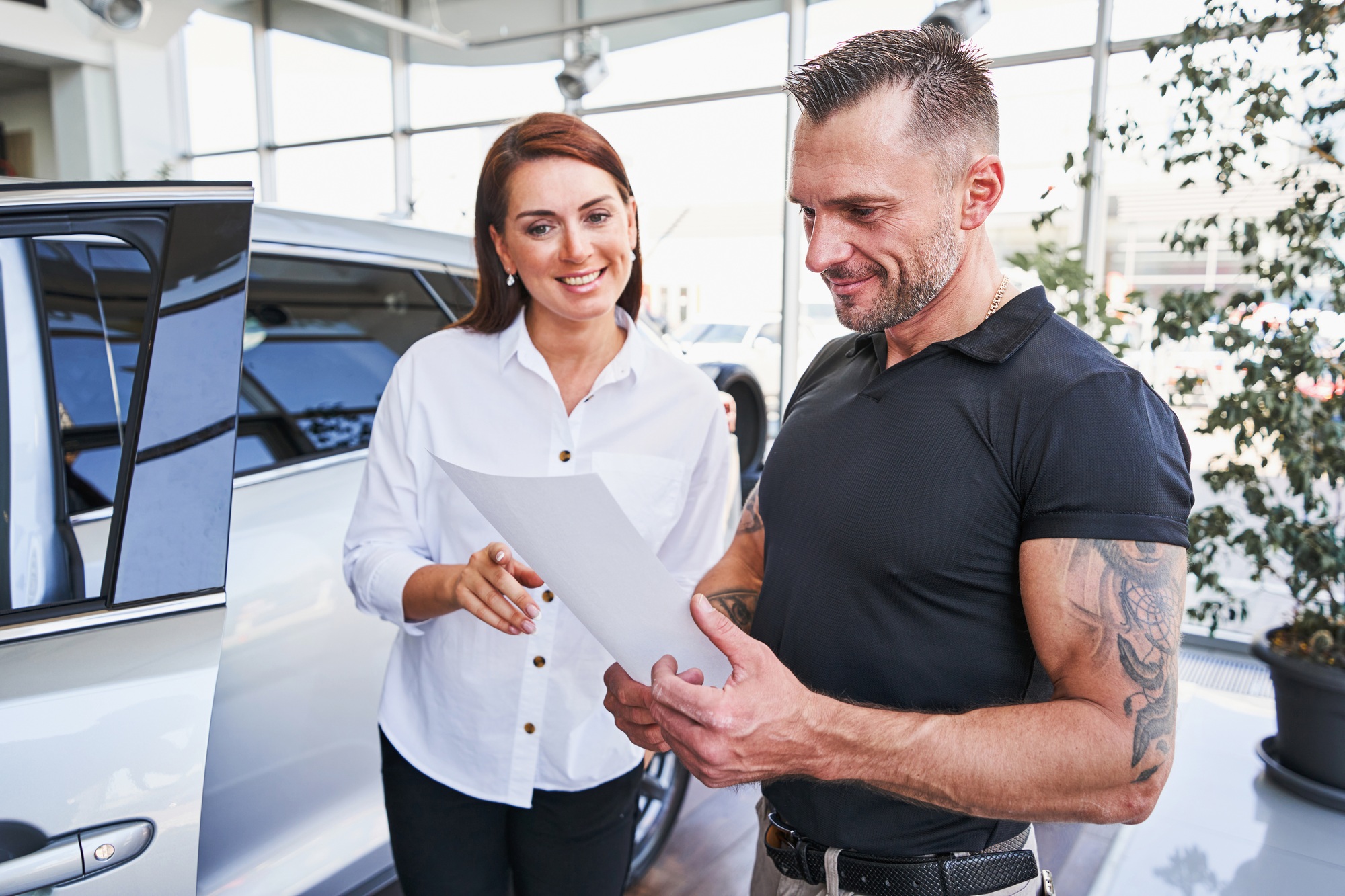 Satisfied client looking at the documents in car dealership